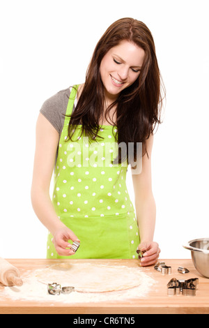 Happy young woman en utilisant des moules de noël sur pâte in front of white background Banque D'Images