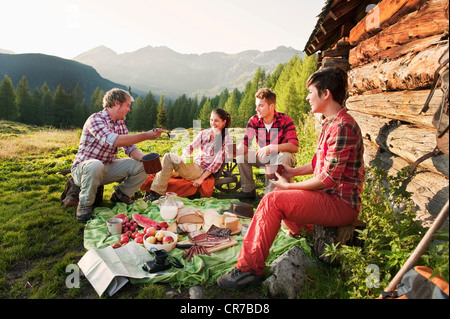 L'Autriche, Salzburg County, hommes et femmes ayant des aires de pique-nique près de chalet de montagne au coucher du soleil Banque D'Images