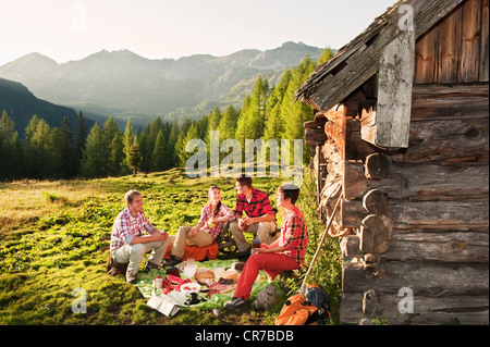 L'Autriche, Salzburg County, hommes et femmes ayant des aires de pique-nique près de chalet de montagne au coucher du soleil Banque D'Images