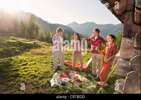 L'Autriche, Salzburg County, hommes et femmes ayant des aires de pique-nique près de chalet de montagne au coucher du soleil Banque D'Images