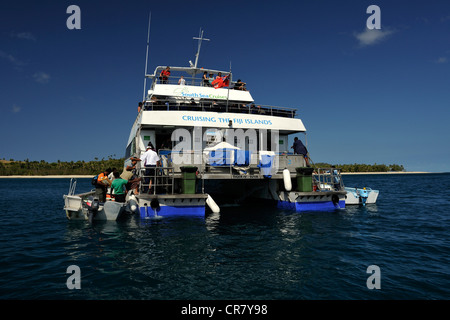 De petites embarcations avec la population locale et les clients viennent aux côtés de Yasawa Flyer qui est arrêté et se trouve à la dérive dans le lagon bleu. Yasawa Islands, Fidji, Banque D'Images