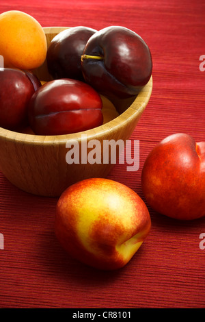 Nectarines, prunes juteuses et les abricots sur fond rouge Banque D'Images