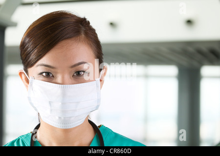 Médecin asiatique porte un masque de visage, gommages et vert stéthoscope. Banque D'Images