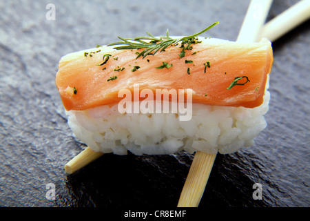 Sushi, nigiri au saumon et baguettes sur une surface en ardoise Banque D'Images