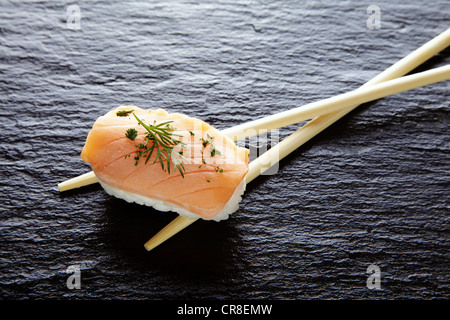 Sushi, nigiri au saumon et baguettes sur une surface en ardoise Banque D'Images