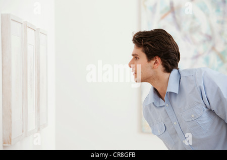 Jeune homme à la recherche de photo dans une galerie d'art Banque D'Images