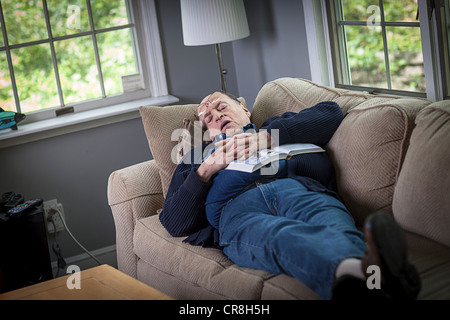 Senior man sleeping on sofa in living room Banque D'Images