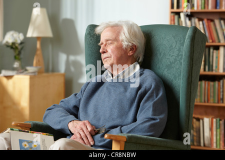 Senior man sleeping in armchair Banque D'Images