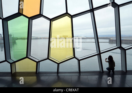 Enfant en regardant à travers les fenêtres en forme d'abeilles dans la façade, nouveau Harpa concert hall à Reykjavik, Islande, Europe Banque D'Images