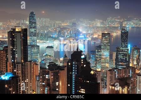 Hong Kong city skyline at night avec Victoria Harbour et gratte-ciel illuminé par des lumières au-dessus de l'eau vu du sommet de la montagne. Banque D'Images