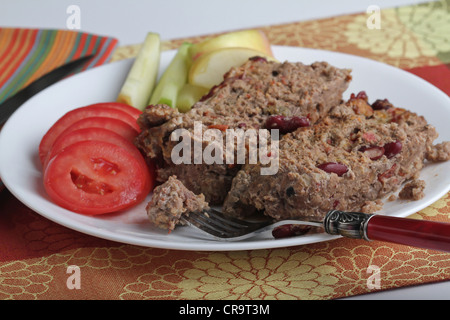 Une assiette de pain fait maison avec des côtés de tomates Roma et les tranches de pommes sur un set de table avec une serviette à rayures. Banque D'Images