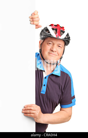 Portrait of a senior cycliste portant casque et posant derrière un panneau blanc isolé sur fond blanc Banque D'Images