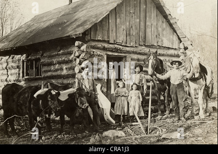 Famille de six en face de cabane rustique Banque D'Images