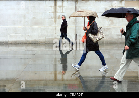 Les personnes qui s'y passé un mur dans la pluie Banque D'Images