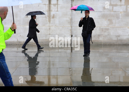 Les personnes qui s'y passé un mur dans la pluie Banque D'Images