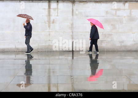 Les personnes qui s'y passé un mur dans la pluie Banque D'Images