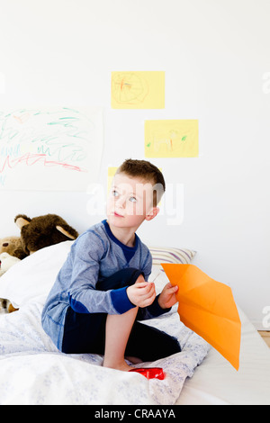 Boy holding dimensions on bed Banque D'Images