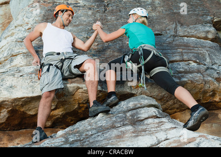 Les grimpeurs scaling steep rock face Banque D'Images