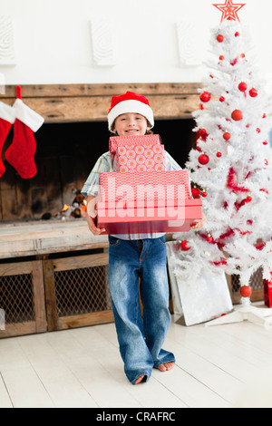 Boy in Santa hat with Christmas gifts Banque D'Images