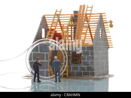 Deux hommes d'observer les chiffres miniature le site de construction d'une maison à l'aide d'une loupe, pour l'image symbolique Banque D'Images