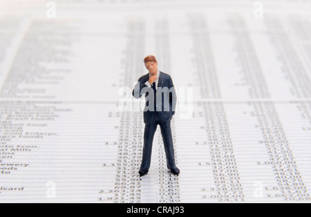 Thoughtful businessman figure debout entre les cours de la bourse Banque D'Images