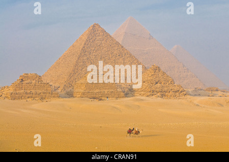 Monter sur des chameaux en face des pyramides de Gizeh, Site du patrimoine mondial de l'UNESCO, l'Égypte, l'Afrique Banque D'Images