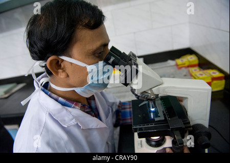 Employé de l'examen d'un échantillon d'expectoration pour la tuberculose agent pathogène sous un microscope, Saint Thomas Home, district de Shibpur, Howrah, Banque D'Images