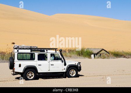 Landrover Defender véhicule hors route et une cabane en bois dans les zones humides de Sandwich Harbour, parc national, une partie de la Banque D'Images