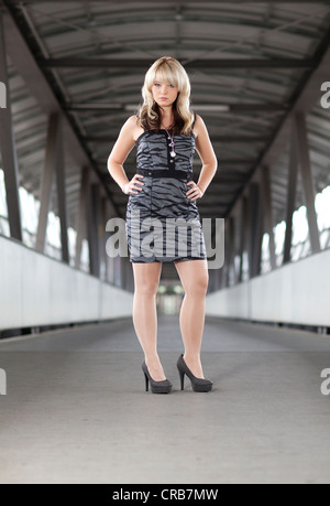 Jeune femme blonde portant une robe grise courte Banque D'Images