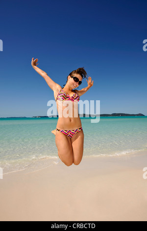 Jeune femme une coupe caper par la mer, symbolique pour profiter de la vie, Whitehaven Beach, l'île de Whitsunday Banque D'Images