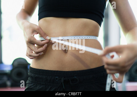 Woman measuring waist in gym Banque D'Images