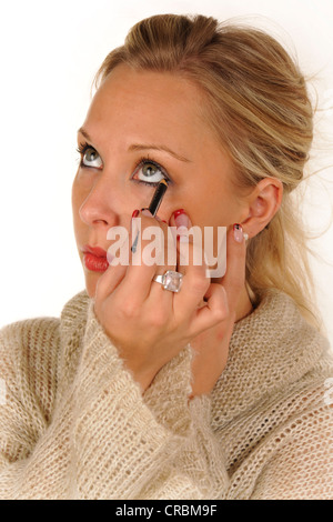 Young woman applying make-up, l'eyeliner Banque D'Images