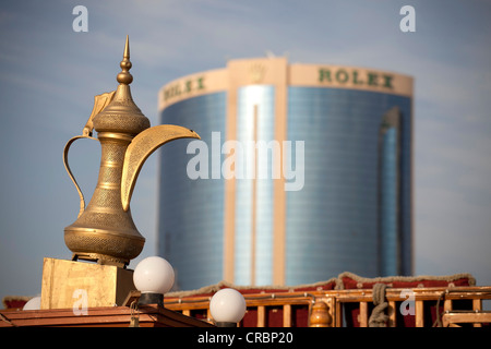 Golden Arabian typique dans la théière avant d'un immeuble de grande hauteur avec le logo Rolex aux côtés de Creek en , Émirats Arabes Unis Banque D'Images