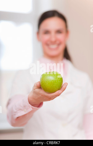 Smiling doctor offrant la pomme verte Banque D'Images