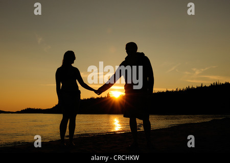 Couple holding hands sur les rives du lac Supérieur au coucher du soleil, de l'Ontario, Canada Banque D'Images