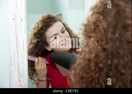 Jeune femme à l'aide d'un sèche-cheveux pour sécher ses cheveux Banque D'Images