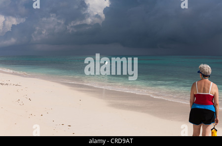 L'observation des oiseaux sur la plage. Une femme regarde une aigrette neigeuse va à l'océan. Banque D'Images