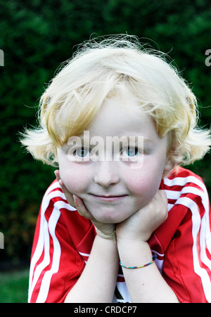 Petit garçon de cinq ans portant une robe de football FC Bayern Munich, tête reposant sur ses mains, portrait Banque D'Images