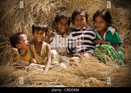 Cinq enfants rire assis sur la paille de riz, au Cambodge, en Asie du Sud-Est, l'Asie Banque D'Images
