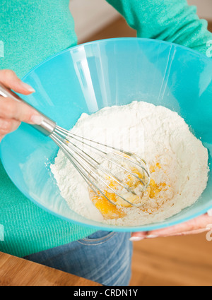 Les oeufs, la farine et d'un fouet dans un bol à mélanger Banque D'Images