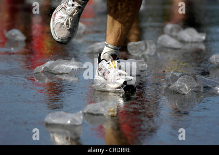 Marathon man, des chaussures d'un coureur sur la rue humide avec des verres en plastique vide Banque D'Images