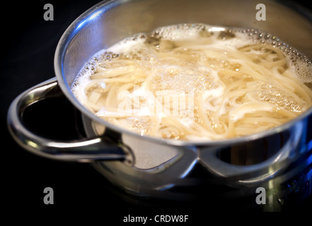 L'eau bouillante avec les nouilles dans la casserole en acier Banque D'Images