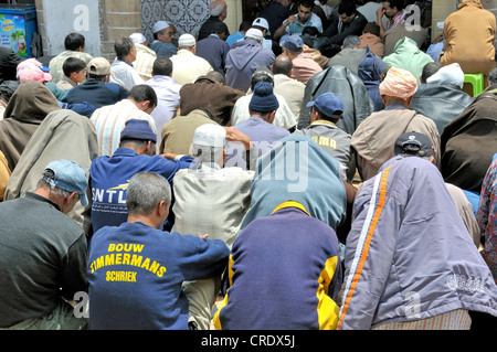 Les hommes assis dans une rue en face d'une mosquée bondée pendant les prières du vendredi, Essaouira, Maroc, Afrique, PublicGround Banque D'Images