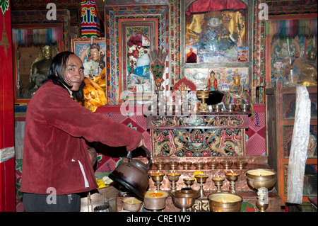 Le bouddhisme tibétain, pèlerin avec les cheveux longs pouring liquid en bougies au beurre de yack, Choku Gompa monastère, route de pèlerinage, Kora Banque D'Images