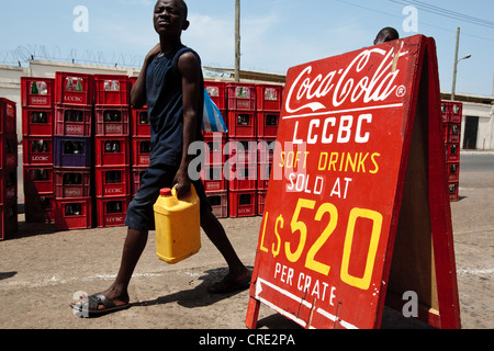 Un garçon passe devant un panneau à vendre des boissons gazeuses de la publicité au marché Temps Rallye à Monrovia, le comté de Montserrado, au Liberia Banque D'Images