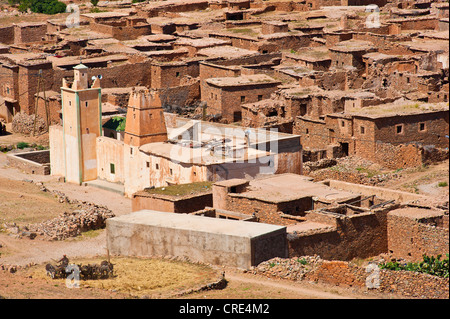 Village de Ait Ourhaine avec une mosquée islamique et d'un minaret, à l'avant, un homme conduisant des ânes sur une case pour battre la paille Banque D'Images