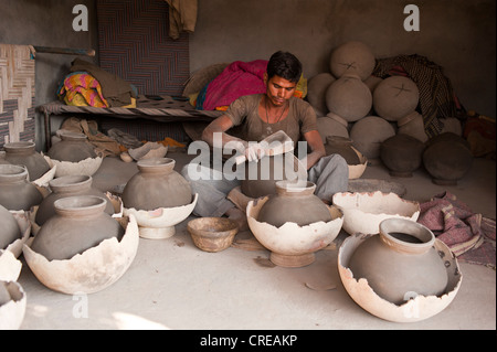 Jeune Indien potter l'eau formant les pots avec un instrument en bois, en face de l'eau de séchage les cruches, Bishnoi, Jodhpur Banque D'Images