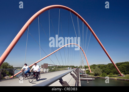 Les cyclistes sur le pont en arc en acier rouge sur le Rhine-Herne-canal au parc Nordstern, Allemagne, Rhénanie du Nord-Westphalie, région de la Ruhr, Bochum Banque D'Images