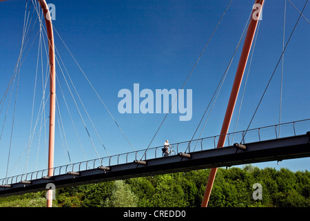 Cycliste sur le pont en arc en acier rouge sur le Rhine-Herne-canal au parc Nordstern, Allemagne, Rhénanie du Nord-Westphalie, région de la Ruhr, Bochum Banque D'Images