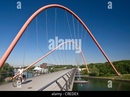 Cycliste sur le pont en arc en acier rouge sur le Rhine-Herne-canal au parc Nordstern, Allemagne, Rhénanie du Nord-Westphalie, région de la Ruhr, Bochum Banque D'Images